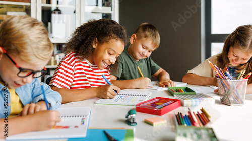 Cheerful ethnic girl solving test with classmates