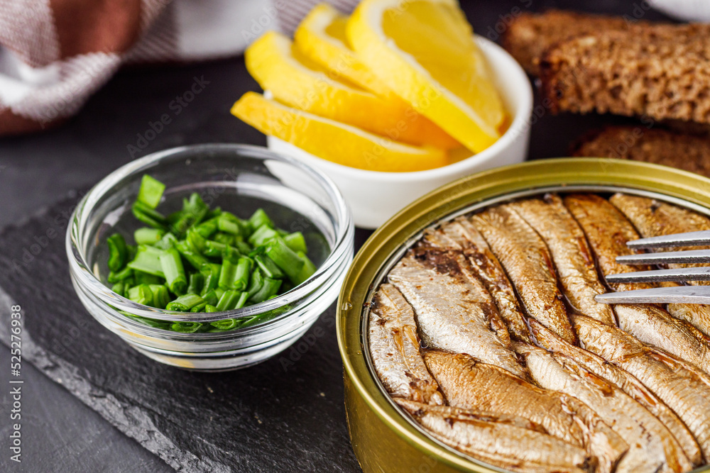 canned sprats in oil on a dark stone background