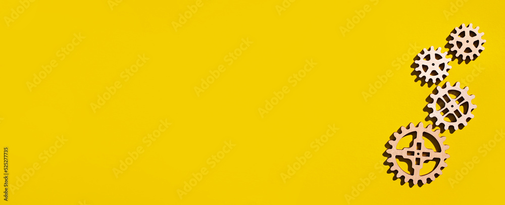 Wooden gears on a yellow background. Flat lay, place for text.