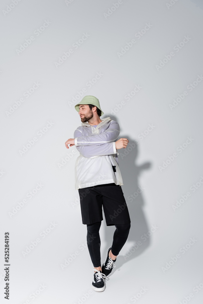 full length of bearded man in trendy sportive outfit and panama hat posing on grey full length of bearded man in trendy sportive outfit and panama hat posing on grey