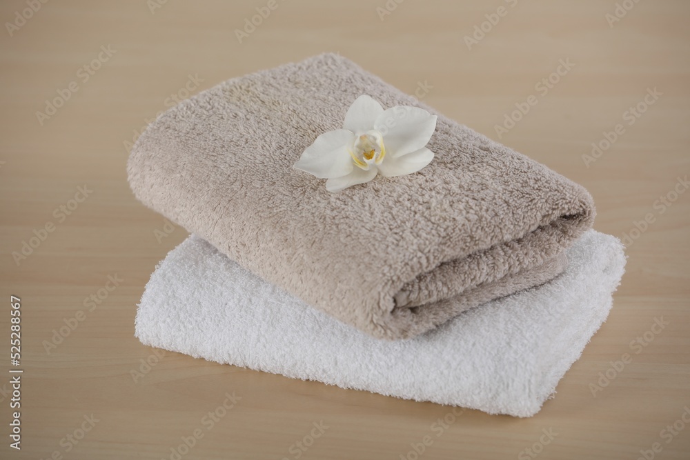 Soft folded towels with orchid flower on wooden table