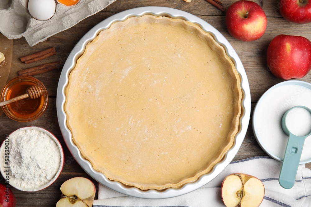 Raw dough and ingredients for traditional English apple pie on wooden table, flat lay Raw dough and ingredients for traditional English apple pie on wooden table, flat lay