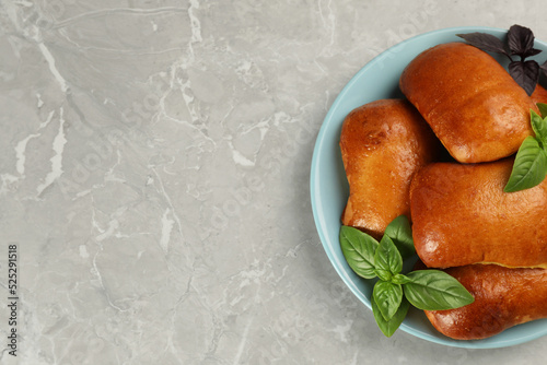 Delicious baked pirozhki and basil on light grey marble table, top view. Space for text photo