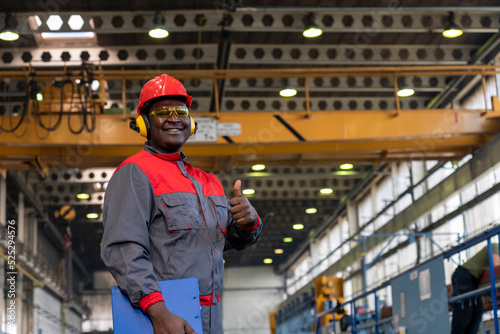 фотографія Cheerful African American Blue-Collar Worker Giving Thumbs Up In A Factory