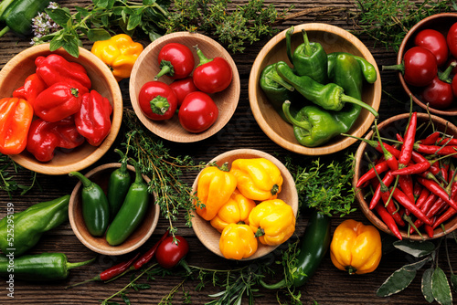 Set of various peppers in bowls with the addition of fresh aromatic herbs  top view