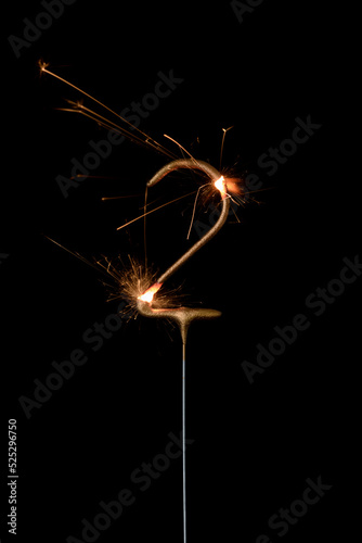 Burning golden sparkler in shape of number two  digit 2  isolated on black background