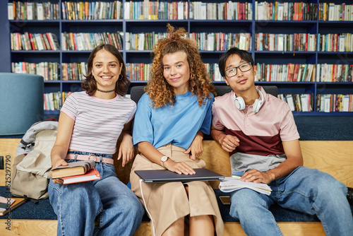 Vibrant portrait of diverse group of students in college library looking at camera and smiling