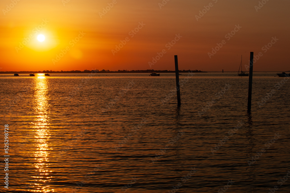 a beautiful sunrise over the sea. the sun rises over the ocean, calm and wave less. The coast is visible, boats are at anchor. There is negative space.