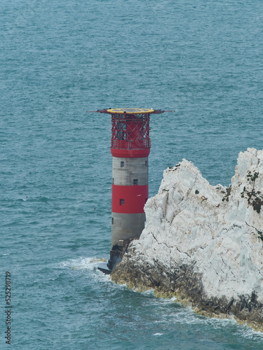 The lighthouse at The Needles in a steely sea and behind jagged, tooth-like outcrops that make clear why the beacon is needed. photo