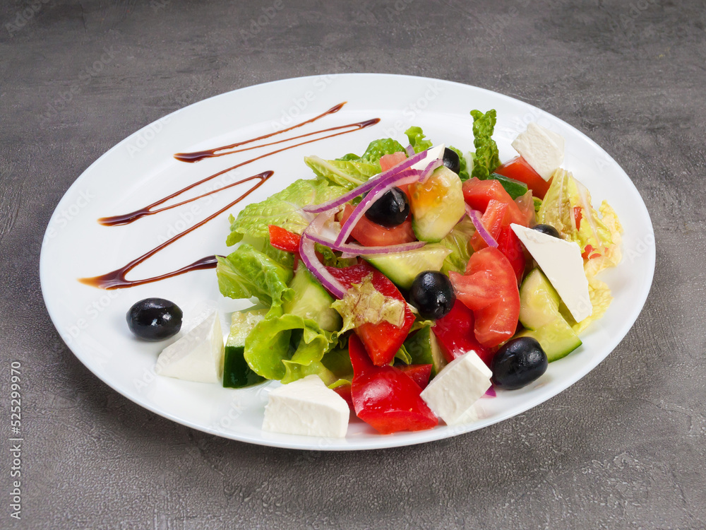 greek salad on a white plate on a gray background. concept: vegetarianism
