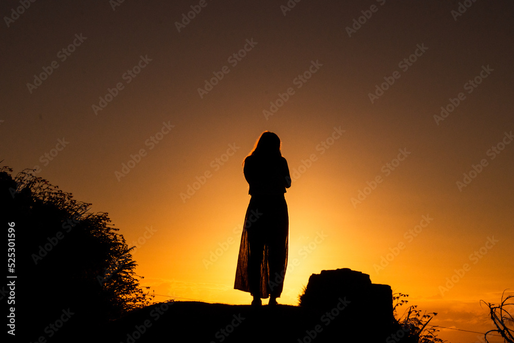Silhouette of person, sunrise or sunset light, sun flare.