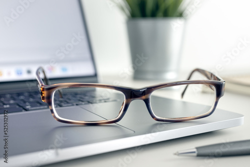 Close up of Eyeglasses on modern laptop on desk. Eye health and vision using computer and modern screen devices