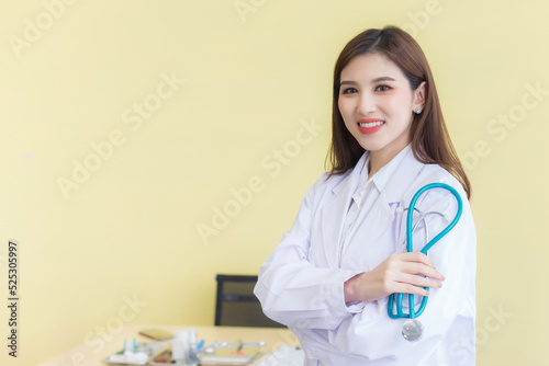 Young beautiful  Asian woman doctor Standing with arms crossed happy and smile in hospital. Wearing a white robe and stethoscope
