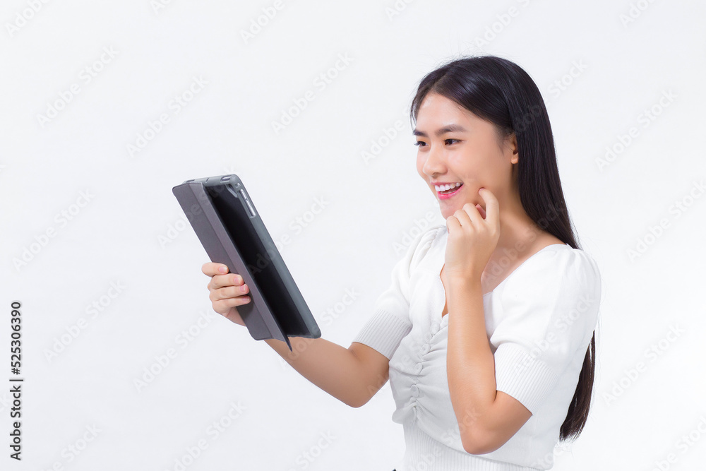 Asian woman in a white shirt looks happily at the tablet with a white background. Asian woman in a white shirt looks happily at the tablet with a white background.