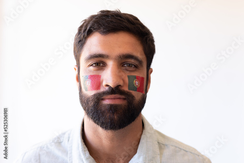 Image of serious multiracial man with flags of portugal on face