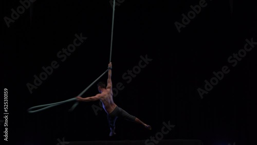 Muscular and fit circus artist perform on aerial rope on high altitude