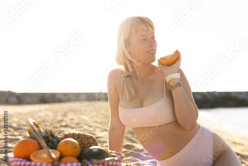 Cheerful young woman enjoy at tropical sand beach. Portrait of happy girl with fruit photo