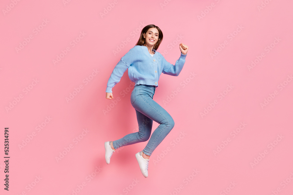 Profile side full length photo of satisfied beautiful cute nice girl dressed blue knit pullover jumping run in air clench fists isolated on pink color background
