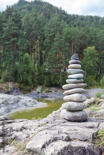 A pyramid of bare stones stacked on top of each other. Stones stacked in the shape of a pyramid on the riverbank against the background of mountains as balance and balance in nature  Zen  Buddhism.