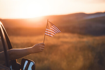 Man in the car holding a waving american USA flag.