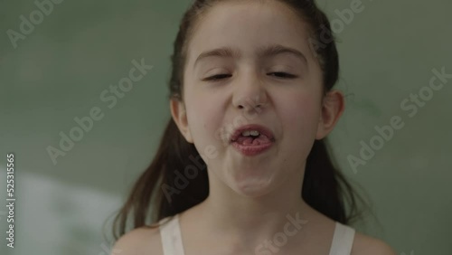 A girl's mouth is a genetic trait inherited from her parents, with her tongue curling into a U-shaped macro. Close-up view of a little schoolgirl girl sticking out her tongue and raising her sides up. photo