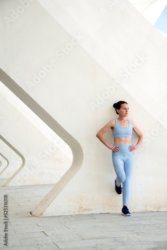 Sporty woman leaning against a concrete wall resting during training,