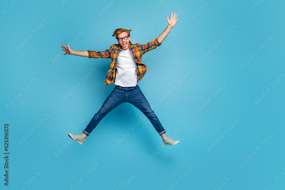 Obraz premium Photo of funky handsome good mood guy open mouth dressed plaid shirt jumping impressed hands to side isolated on blue color background