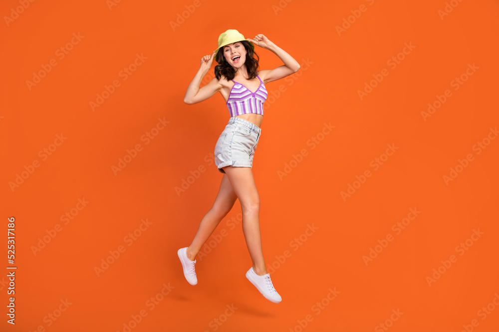 Full length photo of pretty excited lady purple swimwear jumping high walking empty space isolated orange color background Full length photo of pretty excited lady purple swimwear jumping high walking empty space isolated orange color background