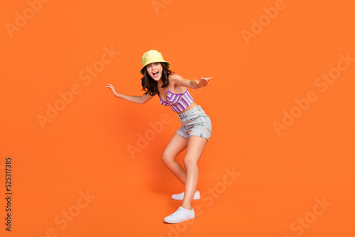 Full length photo of carefree excited lady purple swimwear having fun surf rider isolated orange color background