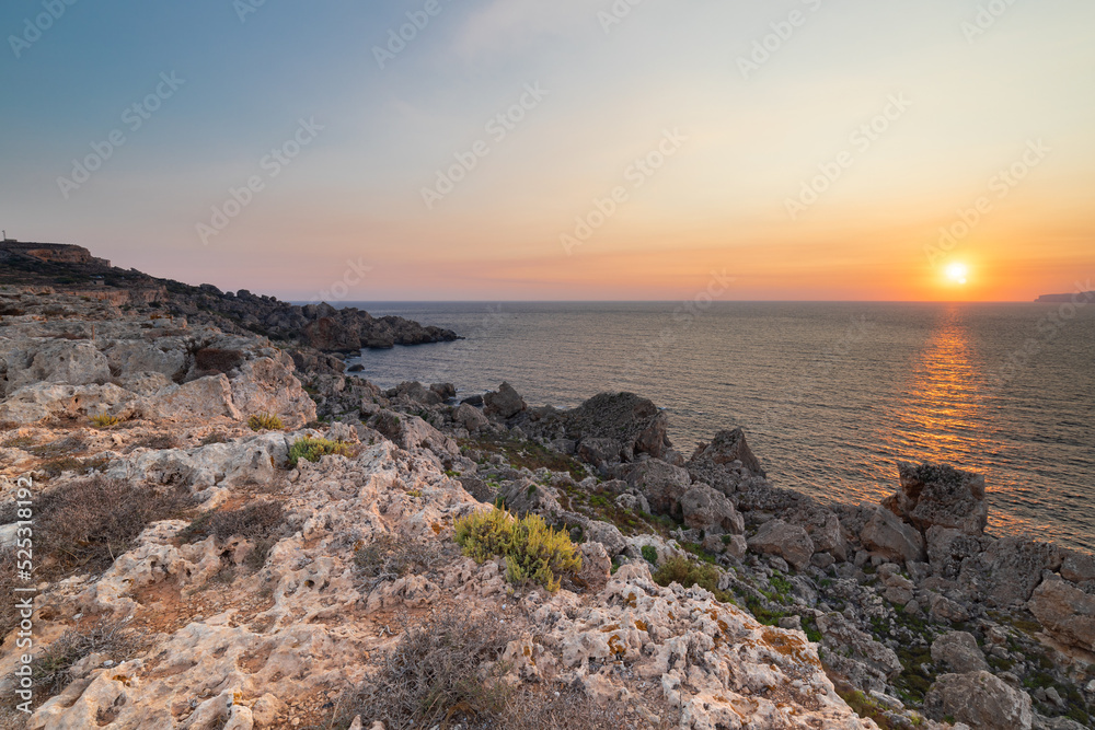 A colourful sunset over the cliffs of Paradis bay in Malta with a view on the Island of Gozo in the Mediterranean Sea. In summer the countries around the Mediterranean enjoy every evening these sunset A colourful sunset over the cliffs of Paradis bay in Malta with a view on the Island of Gozo in the Mediterranean Sea. In summer the countries around the Mediterranean enjoy every evening these sunset