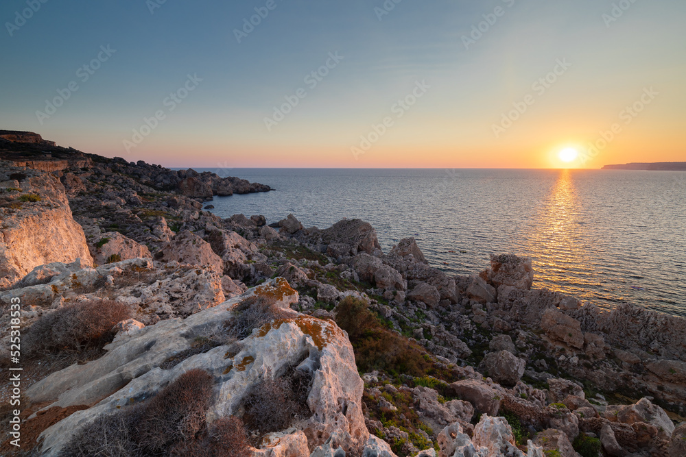 A colourful sunset over the cliffs of Paradis bay in Malta with a view on the Island of Gozo in the Mediterranean Sea. In summer the countries around the Mediterranean enjoy every evening these sunset A colourful sunset over the cliffs of Paradis bay in Malta with a view on the Island of Gozo in the Mediterranean Sea. In summer the countries around the Mediterranean enjoy every evening these sunset