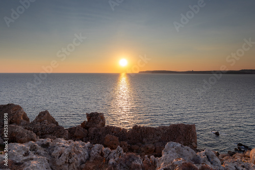 A colourful sunset over the cliffs of Paradis bay in Malta with a view on the Island of Gozo in the Mediterranean Sea. In summer the countries around the Mediterranean enjoy every evening these sunset