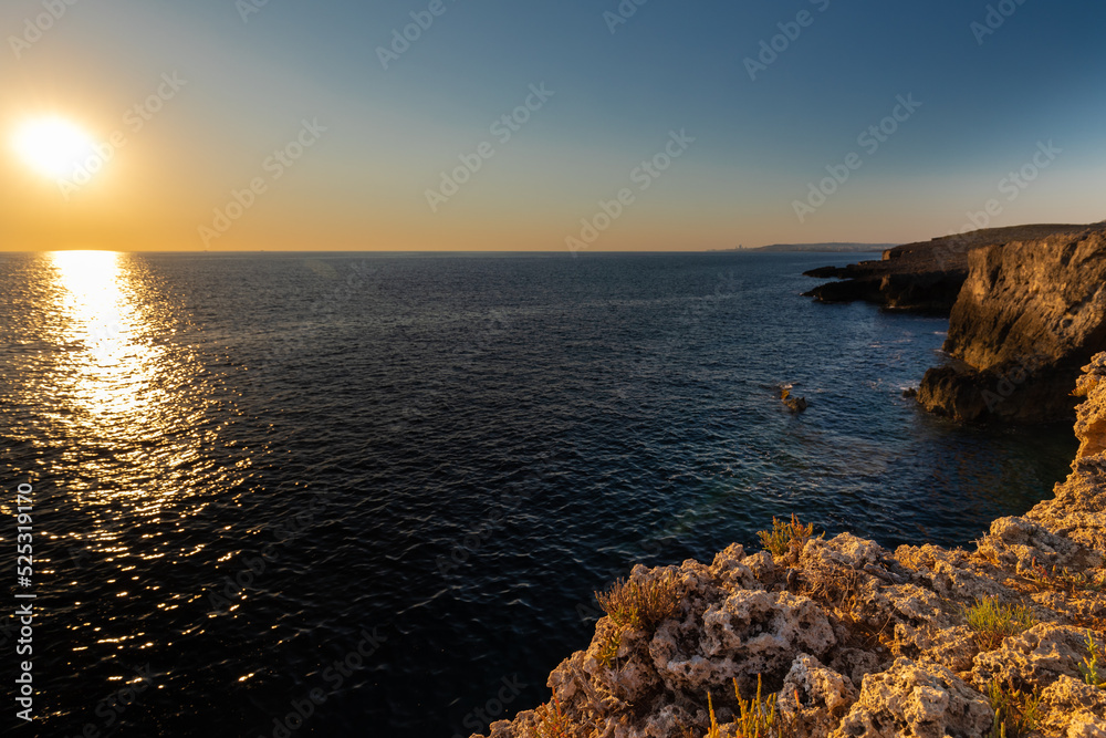 Amazing sunrise over the rising cliffs and rocks at Mellieha in the north west of Malta, with spectacular colors in the sky and reflections of the sun in het Mediterranean sea