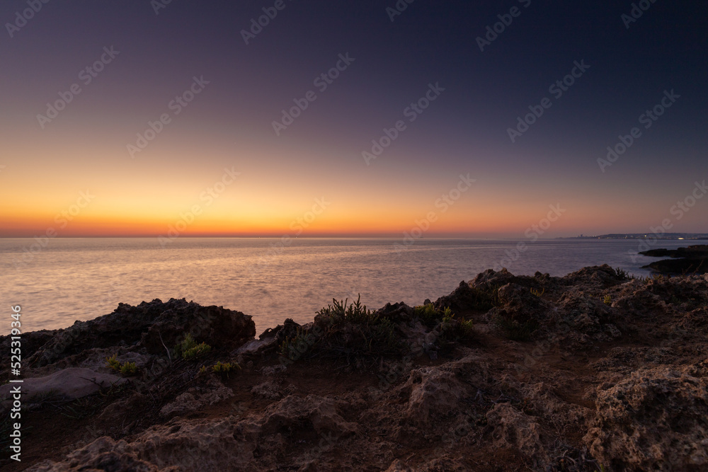 Amazing sunrise over the rising cliffs and rocks at Mellieha in the north west of Malta, with spectacular colors in the sky and reflections of the sun in het Mediterranean sea