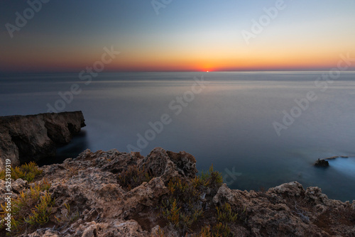 Amazing sunrise over the rising cliffs and rocks at Mellieha in the north west of Malta, with spectacular colors in the sky and reflections of the sun in het Mediterranean sea