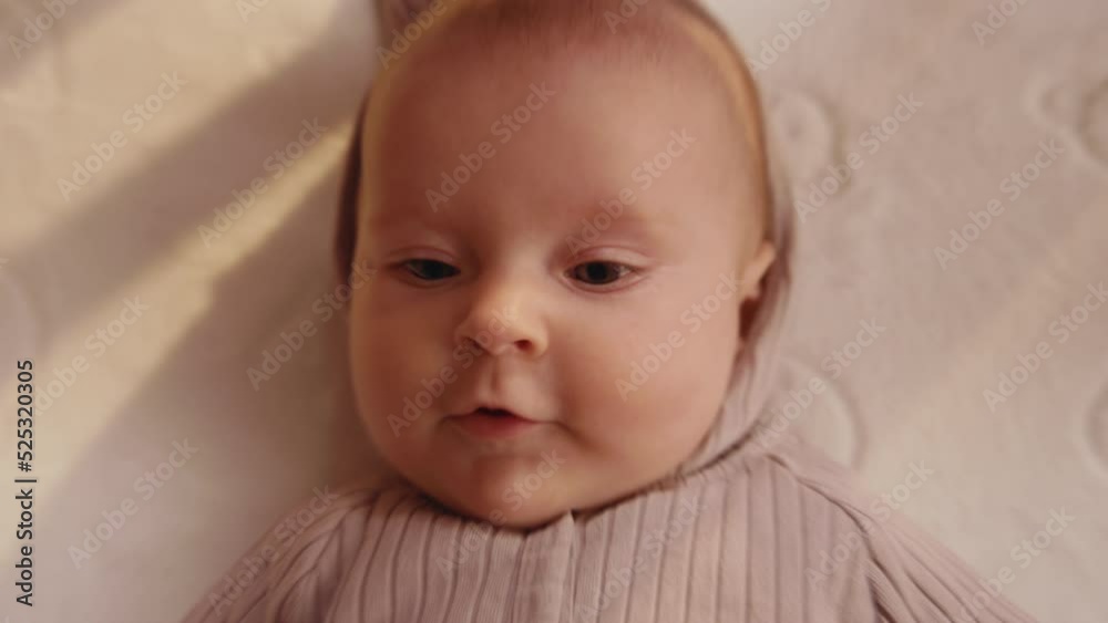 Overhead view of funny baby makes surprised face. Close-up footage of cute Caucasian baby boy. Infant resting lying down on crib bed at home. Motherhood and child concept. Home Overhead view of funny baby makes surprised face. Close-up footage of cute Caucasian baby boy. Infant resting lying down on crib bed at home. Motherhood and child concept. Home