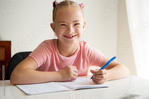 Girl with Down Syndrome doing homework at home, getting ready to go back to school