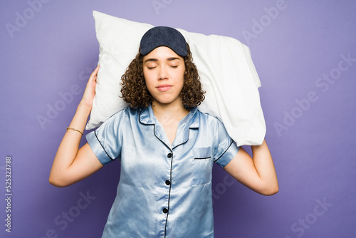 Tired young woman in pajamas sleeping and dreaming against a purple background