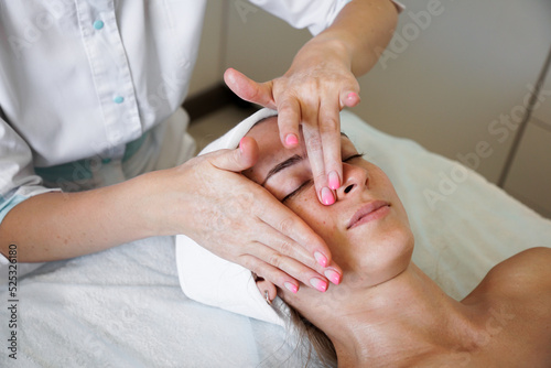 Pretty yanog woman receiving face massage, closeup photo. Beauty treatments. Beautician