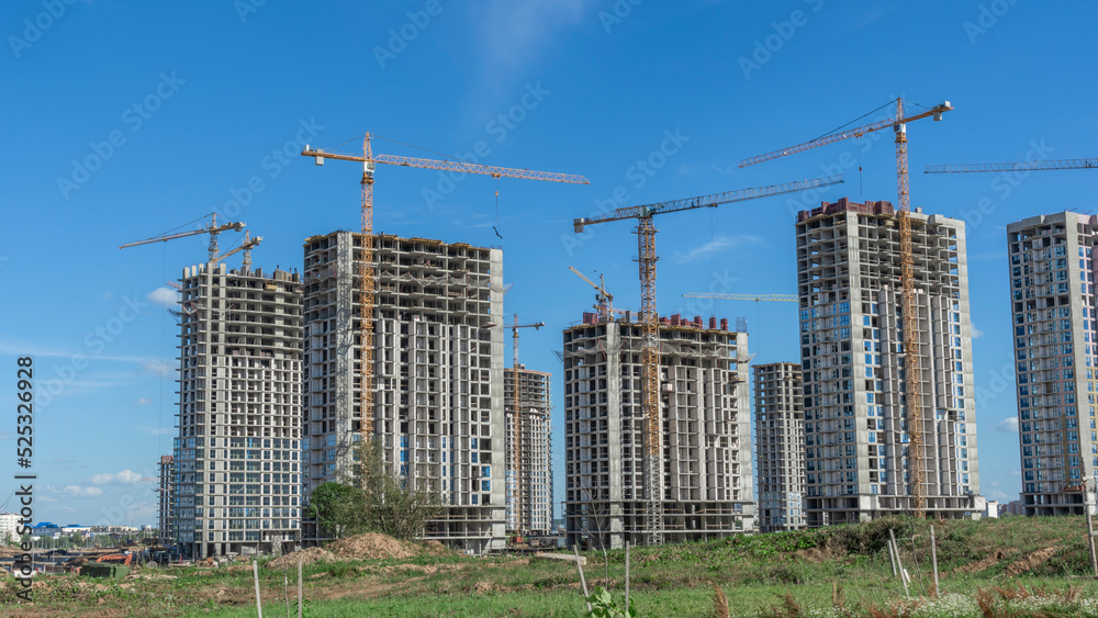 Construction of a multi-story residential buildings. A lot of construction equipment, cranes work. Construction site.