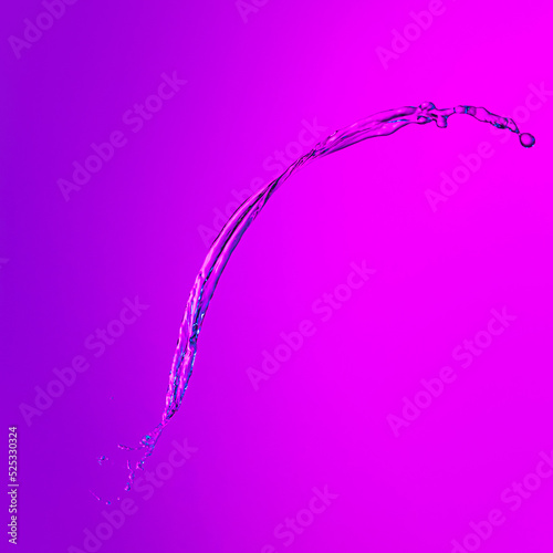 Flying splash transparent liquid or water on lilac color background in neon light. Minimalism, art, fashion