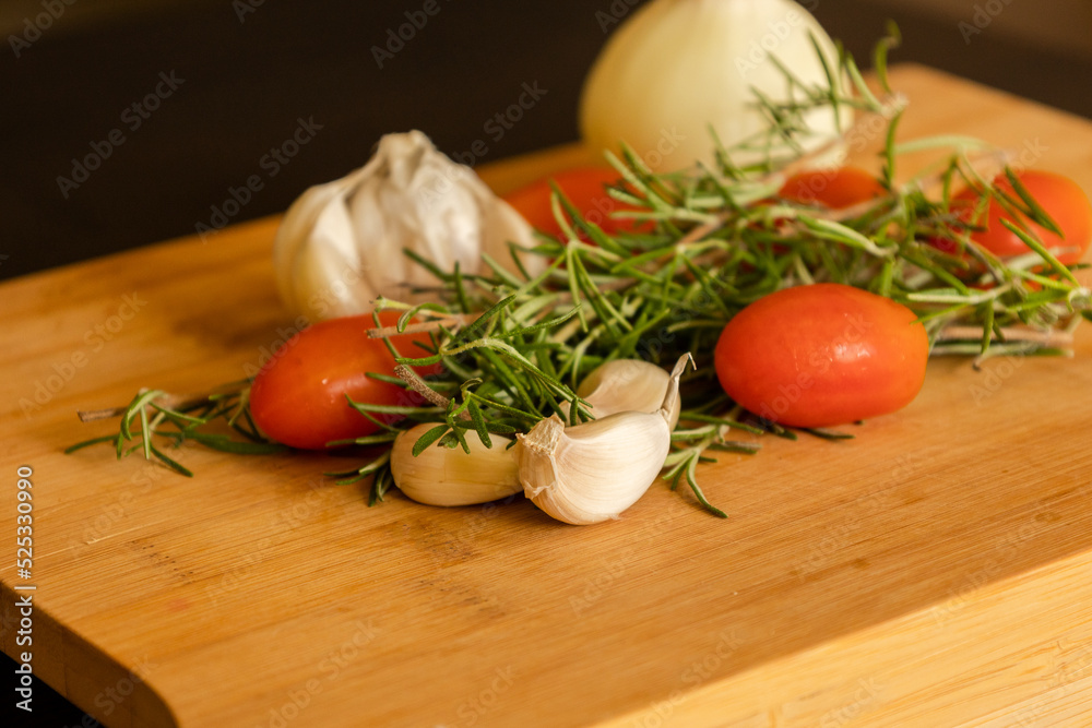 close-ups of tomatoes, rosemary and garlic on wooden board close-ups of tomatoes, rosemary and garlic on wooden board