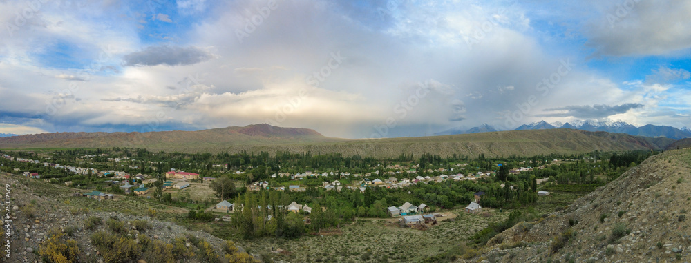 180 degree panorama of the village of Kyzyl Tuu with dramatic sky in Kyrgyzstan.