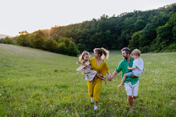 Happy young family spending time together outside in green nature.