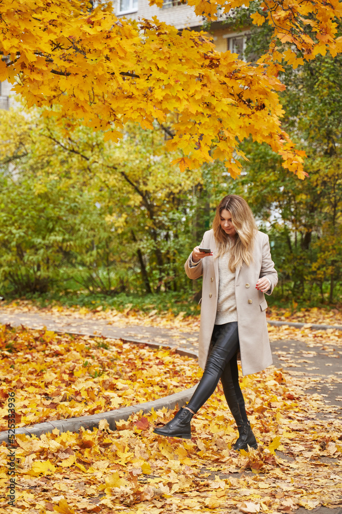 a young woman walks and takes off her legs, which throw up fallen autumn yellow leaves a young woman walks and takes off her legs, which throw up fallen autumn yellow leaves
