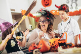 Happy family of mother and children prepare for Halloween pumpkins decorate the home