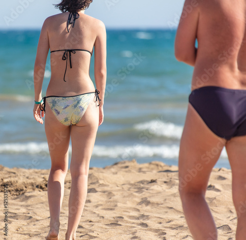 A man and a girl in swimsuits on the shore by the sea.