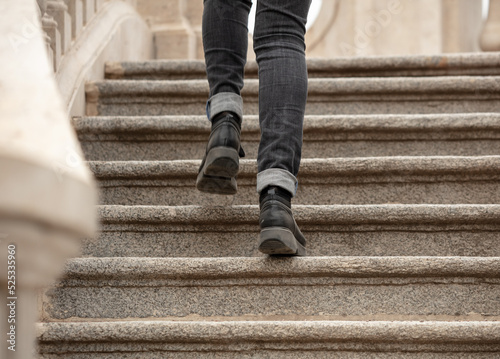 A girl in black jeans walks up the stairs.