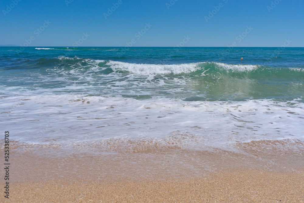 Clear emerald green sea with white foam and clean sandy beach