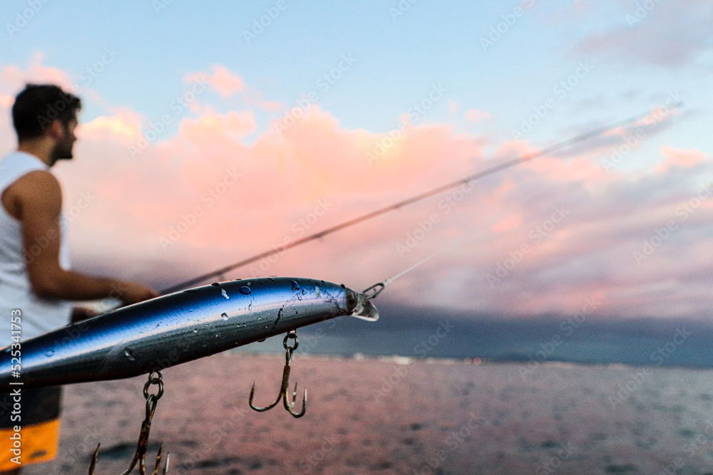 man spinning fishing with the sunset in the background